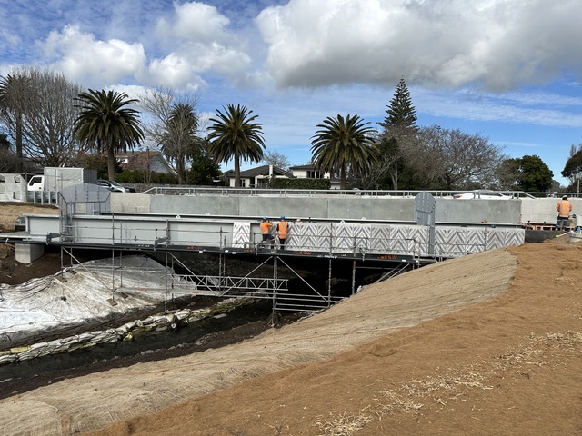 Pedestrian bridge with a patterned steel screen over water